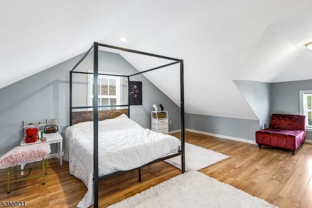 bedroom with vaulted ceiling, wood finished floors, and baseboards
