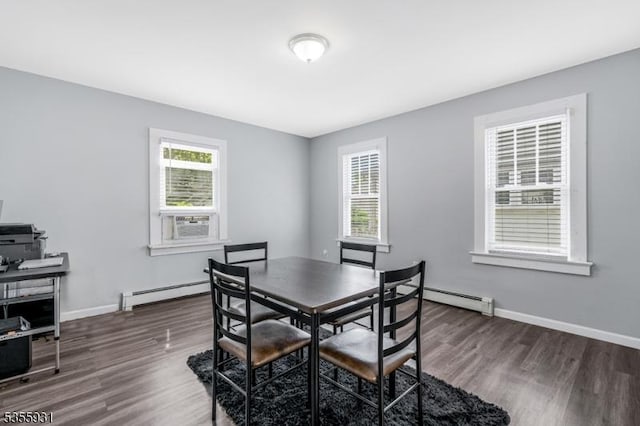 dining space with a baseboard radiator, a baseboard heating unit, healthy amount of natural light, and wood finished floors