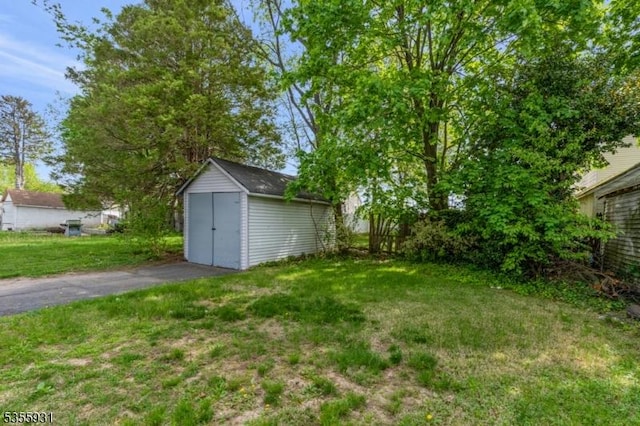 view of green lawn featuring a storage shed and an outbuilding