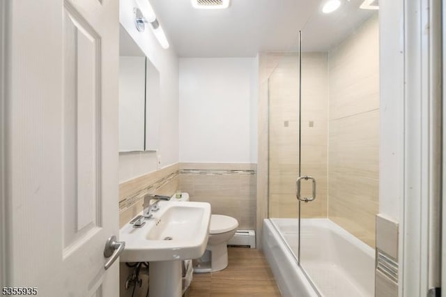 74 Emerald Pl, Clark Twp, NJ 07066 - full bathroom featuring a baseboard radiator, toilet, tile walls, combined bath / shower with glass door, and wood finished floors