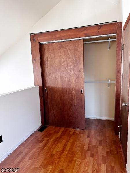 unfurnished bedroom with lofted ceiling and wood finished floors