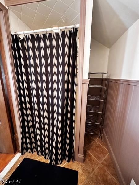 full bathroom featuring a wainscoted wall, tile patterned flooring, and curtained shower