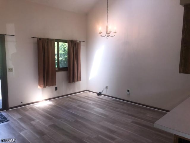 unfurnished dining area featuring a chandelier, wood finished floors, and baseboards