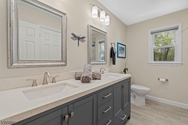 53 Woodland Ave, Morris Twp, NJ 07960 - bathroom with toilet, baseboards, double vanity, and wood finished floors