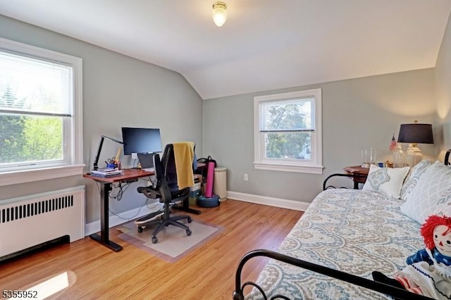 bedroom with radiator, lofted ceiling, multiple windows, wood finished floors, and baseboards