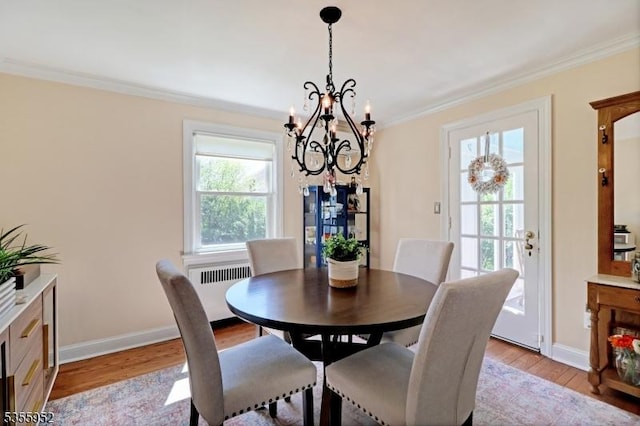 dining space with radiator heating unit, a chandelier, crown molding, light wood-style floors, and baseboards