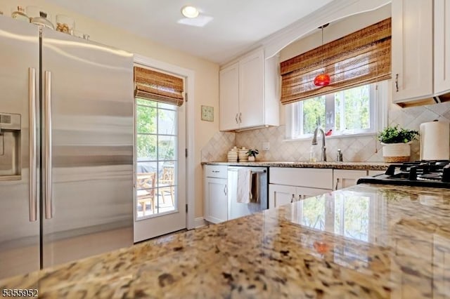 kitchen with appliances with stainless steel finishes, plenty of natural light, and white cabinets