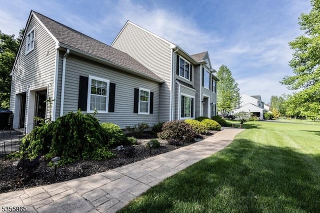 view of side of property featuring a yard and a shingled roof