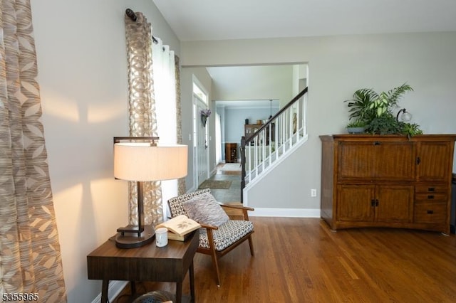living area with wood finished floors, stairs, and baseboards