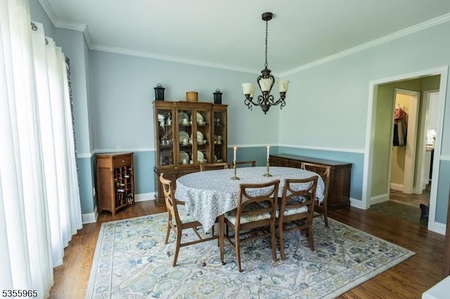 dining room with a chandelier, crown molding, wood finished floors, and baseboards