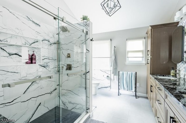 bathroom with a marble finish shower, vanity, toilet, tile patterned floors, and baseboards