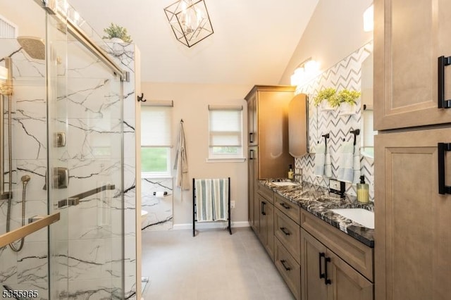 bathroom featuring a marble finish shower, double vanity, vaulted ceiling, baseboards, and radiator