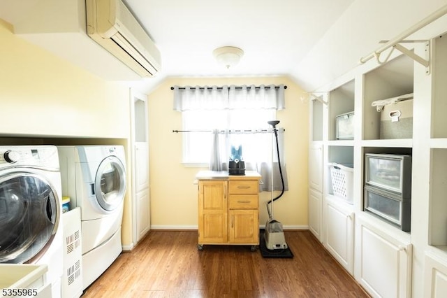 laundry area with independent washer and dryer, a wall mounted air conditioner, wood finished floors, and baseboards
