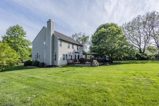 rear view of house with a gazebo, a chimney, a yard, and a wooden deck