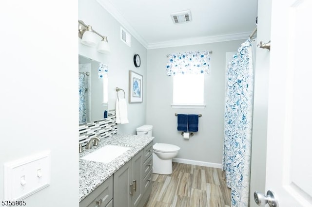 bathroom with crown molding, toilet, vanity, tasteful backsplash, and baseboards
