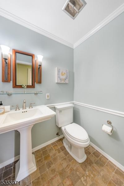 bathroom featuring toilet, ornamental molding, and baseboards