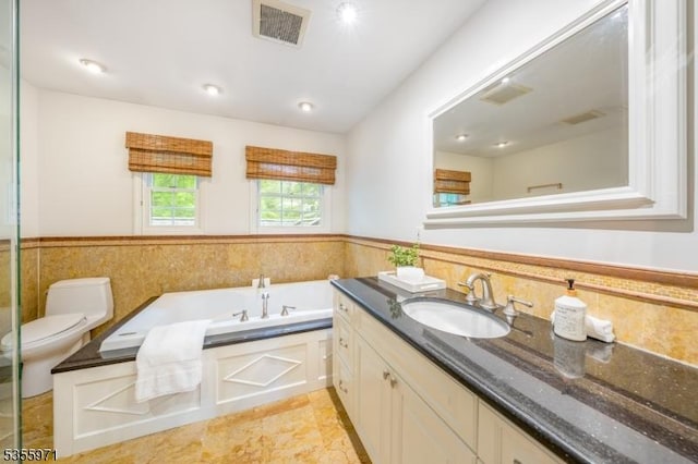 bathroom featuring a wainscoted wall, a garden tub, vanity, and toilet