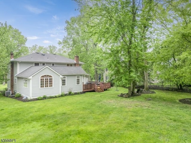 rear view of property with a chimney, a yard, a wooden deck, and central AC unit