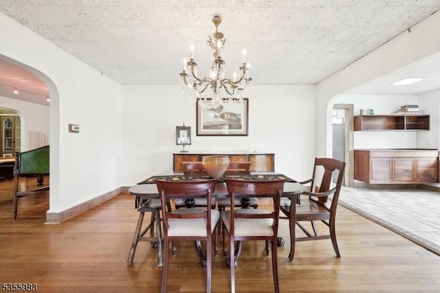 10 Highland Pl, West Orange Twp, NJ 07052 - dining space featuring light wood-style floors, arched walkways, a chandelier, and baseboards