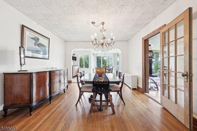 10 Highland Pl, West Orange Twp, NJ 07052 - dining room featuring light wood-style flooring, a chandelier, arched walkways, french doors, and baseboards