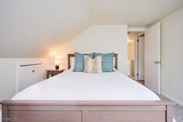 carpeted bedroom with lofted ceiling and baseboards