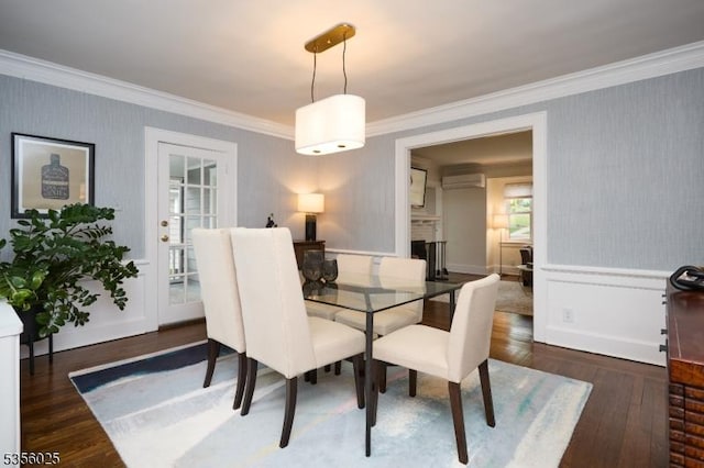 dining room featuring ornamental molding, wood finished floors, a fireplace, wainscoting, and wallpapered walls