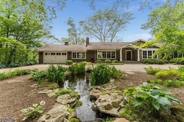 12 Woodland Rd, Franklin Twp, NJ 08867 - ranch-style house with a garage, dirt driveway, a chimney, a small pond, and stone siding