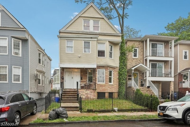 townhome / multi-family property featuring a fenced front yard and stone siding