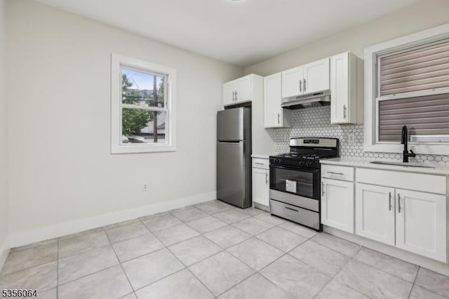 kitchen with appliances with stainless steel finishes, under cabinet range hood, a sink, light countertops, and tasteful backsplash