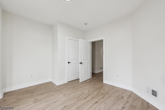 spare room featuring light wood-type flooring and baseboards