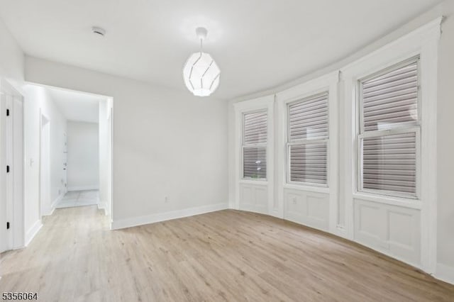 unfurnished dining area with light wood-style flooring and baseboards