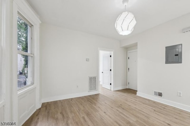 unfurnished room with electric panel, wood finished floors, and baseboards