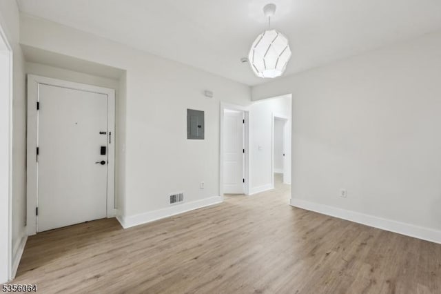 unfurnished room featuring light wood finished floors, electric panel, and baseboards