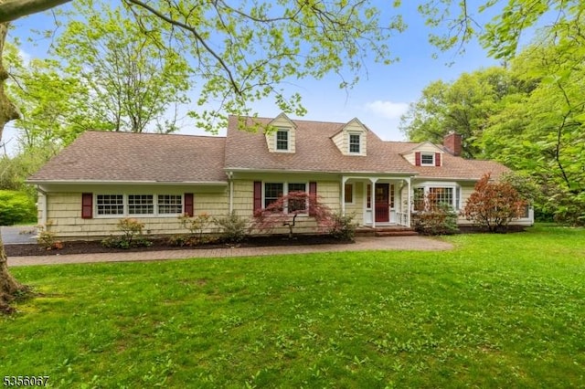 cape cod home featuring a front lawn, a chimney, and covered porch