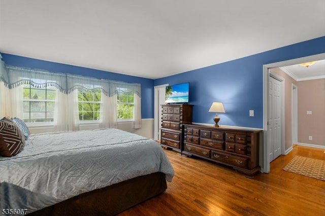 bedroom featuring wood finished floors, ornamental molding, and baseboards