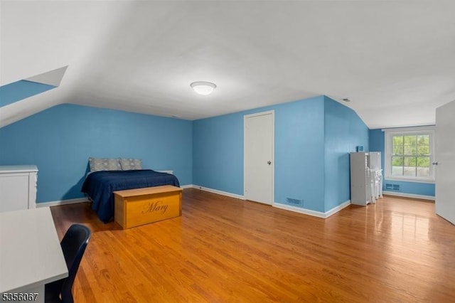 bedroom featuring lofted ceiling, wood finished floors, and baseboards
