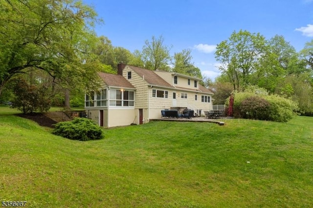back of property featuring a sunroom, a yard, a chimney, and a patio area