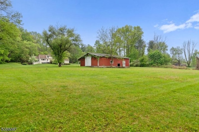 view of green lawn with an outbuilding and a pole building