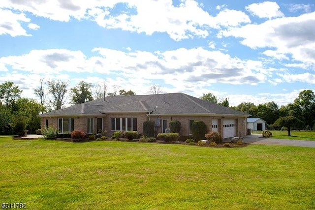 view of front of house featuring asphalt driveway, a garage, and a front lawn