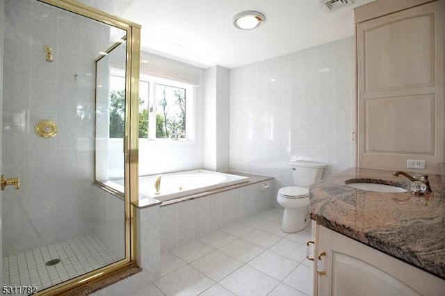full bath featuring tile patterned flooring, tile walls, a stall shower, vanity, and toilet