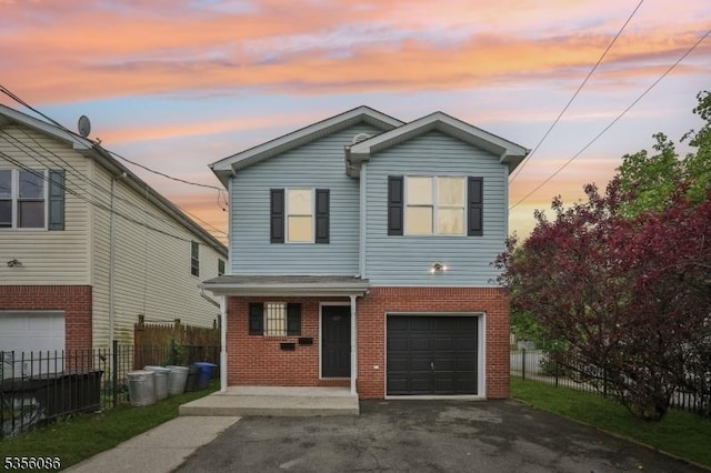traditional-style home featuring brick siding, fence, asphalt driveway, and an attached garage