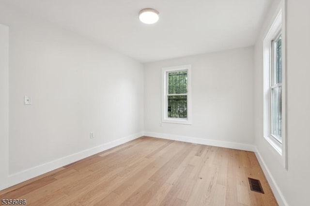 unfurnished room with light wood-type flooring and baseboards