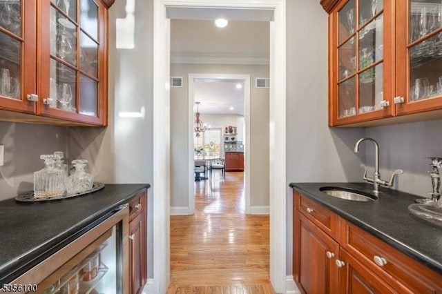indoor bar featuring ornamental molding, light wood-style flooring, wine cooler, and baseboards