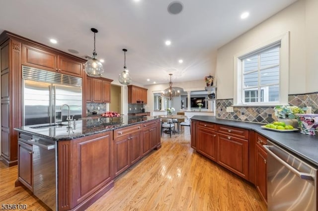 kitchen with stainless steel appliances, a sink, light wood-type flooring, a chandelier, and recessed lighting