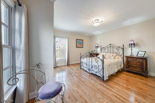 bedroom featuring light wood-type flooring, baseboards, and crown molding