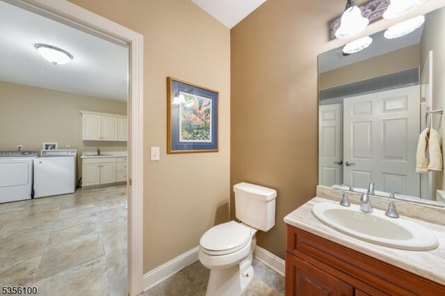 bathroom with washing machine and clothes dryer, baseboards, vanity, toilet, and tile patterned floors