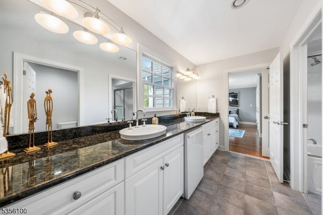 full bath featuring double vanity, baseboards, and a bathtub
