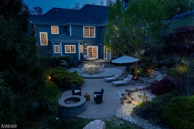 rear view of property featuring a fire pit and a patio area