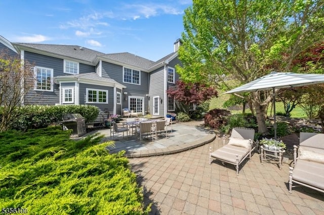 rear view of property featuring a patio area, a chimney, and an outdoor hangout area