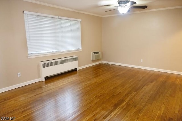 spare room with radiator, ornamental molding, wood finished floors, a ceiling fan, and baseboards